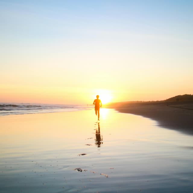 Person walking on beach at sunset